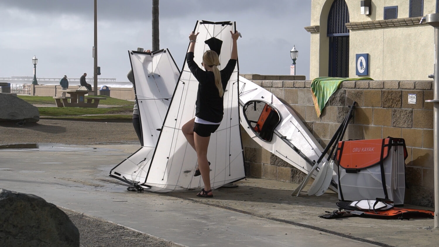 Bild zeigt eine Frau, die das Oru Kayak zu einer Box zusammen faltet