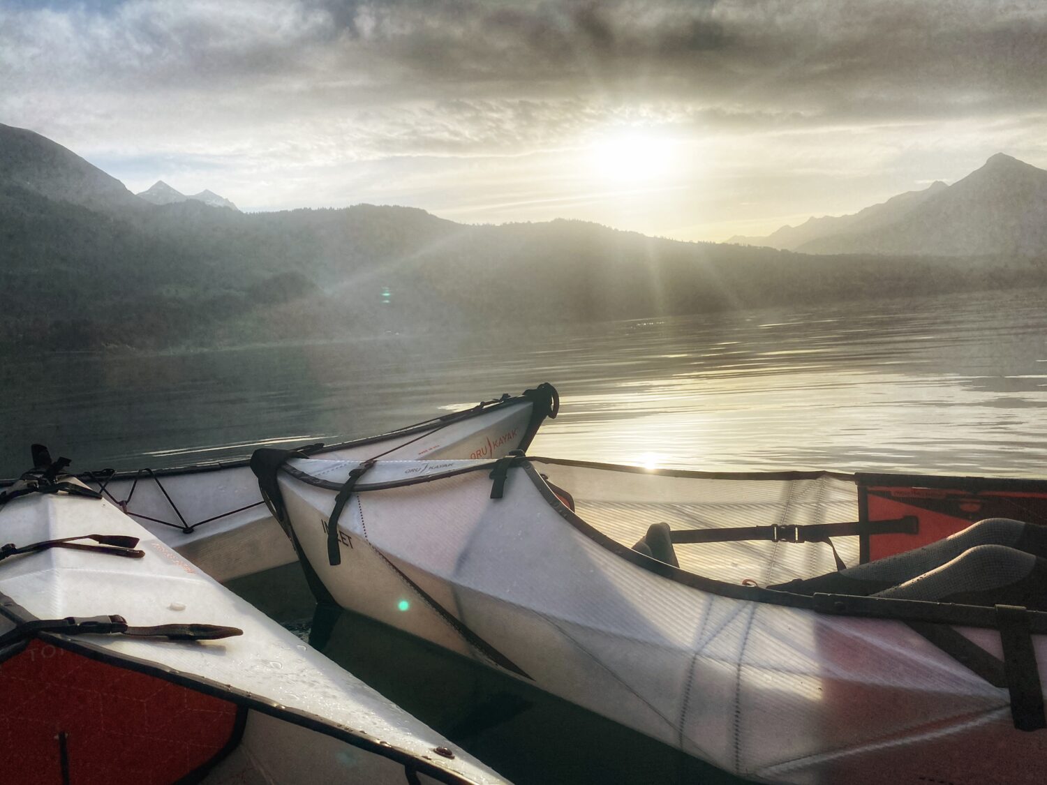 Bild zeigt unterscshiedliche Oru Kayak Modelle bei Sonnenuntergang auf dem Thunersee